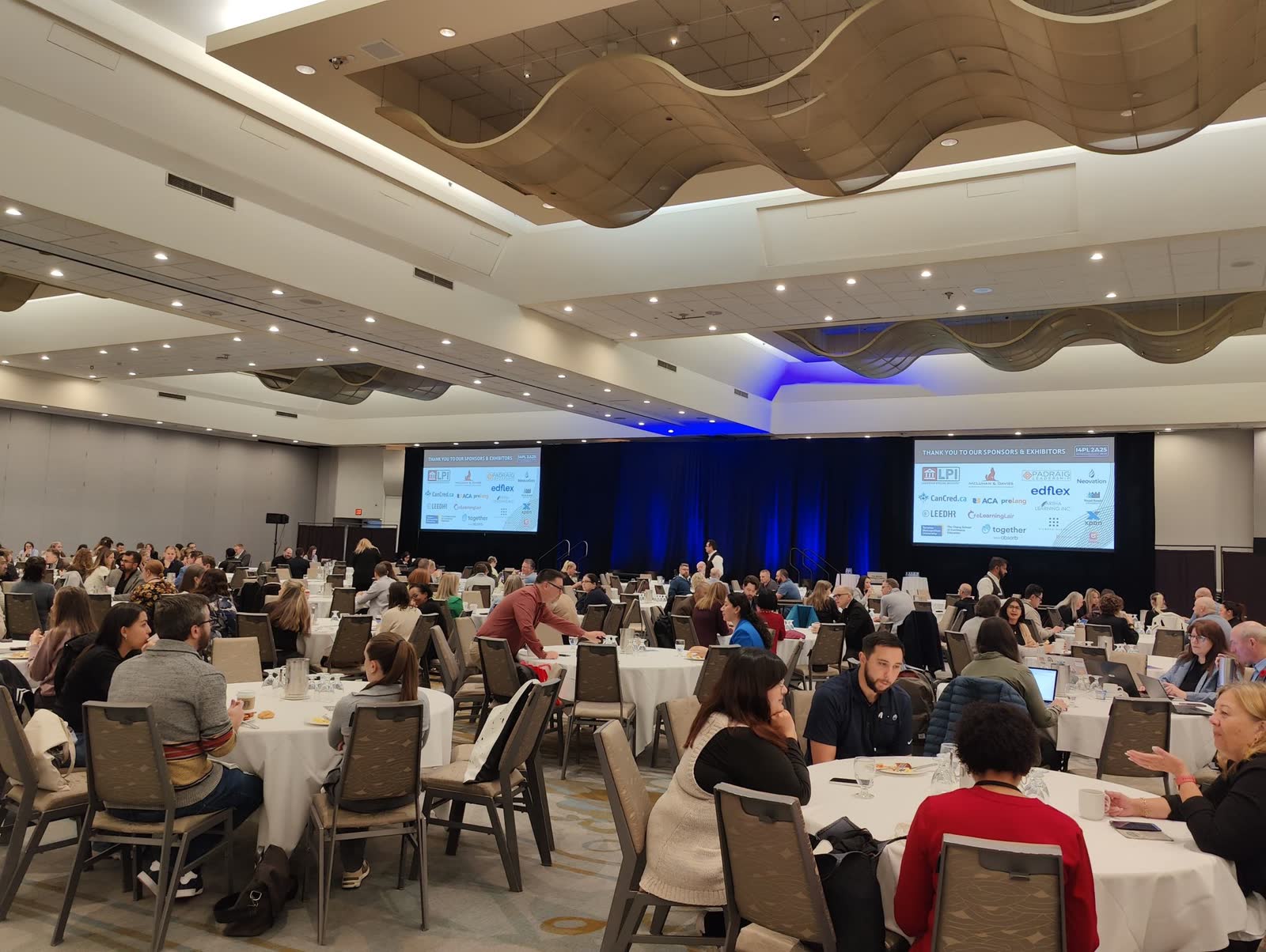The I4PL conference ballroom filled with delegates at round tables